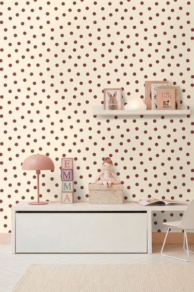 Hell gestaltetes Kinderzimmer mit einer Tapete mit Punktemuster, einem weißen Sideboard, einer Tischleuchte und dekorativen Elementen.