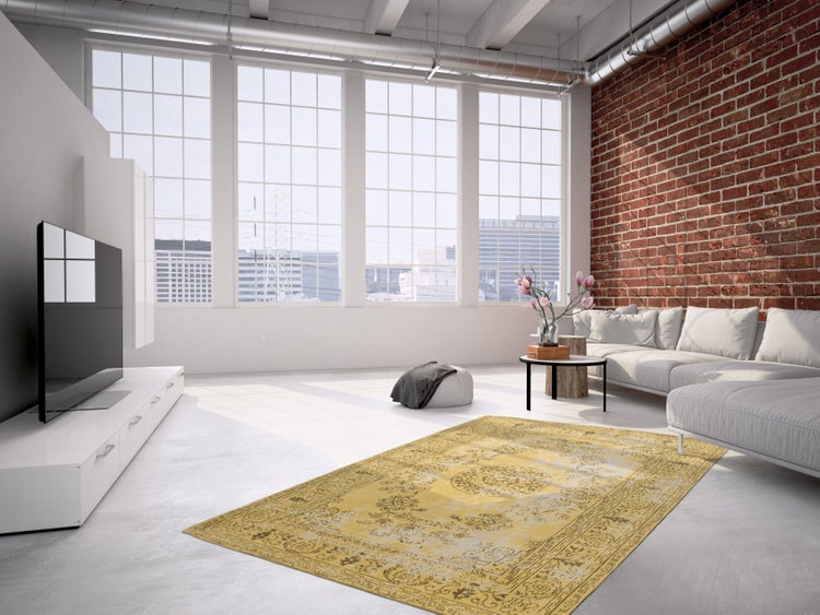 Helles Wohnzimmer im Loft Stil mit Backsteinwand, hohen Fenstern, weißem Sofa, TV Möbel und einem gemusterten Teppich auf dem Boden.