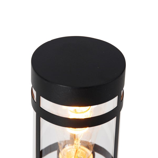 Nahaufnahme einer zylindrischen Außenleuchte aus schwarzem Metall und klarem Glas mit leuchtendem Leuchtmittel.