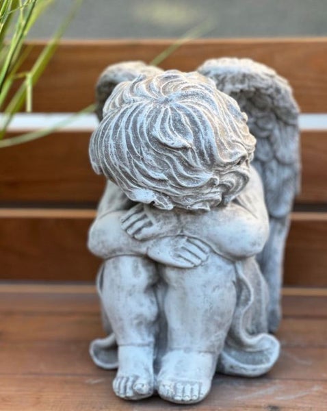 Sitzende Engelsfigur aus Steinguss mit gesenktem Kopf und Flügeln für Garten und Grab.