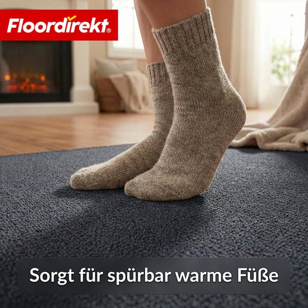 Füße in Wollsocken auf einem Teppich vor einem Kamin