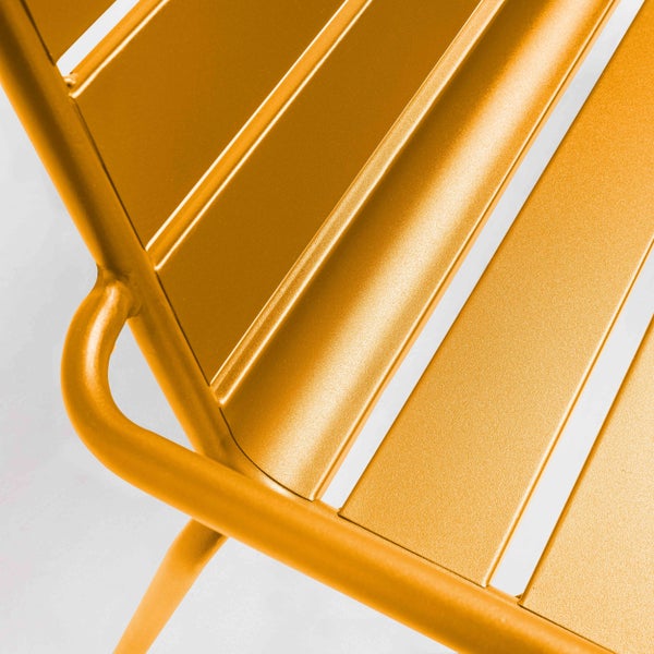 Nahaufnahme eines gelben Gartenstuhls aus Metall mit Lamellen und Rohrgestell.