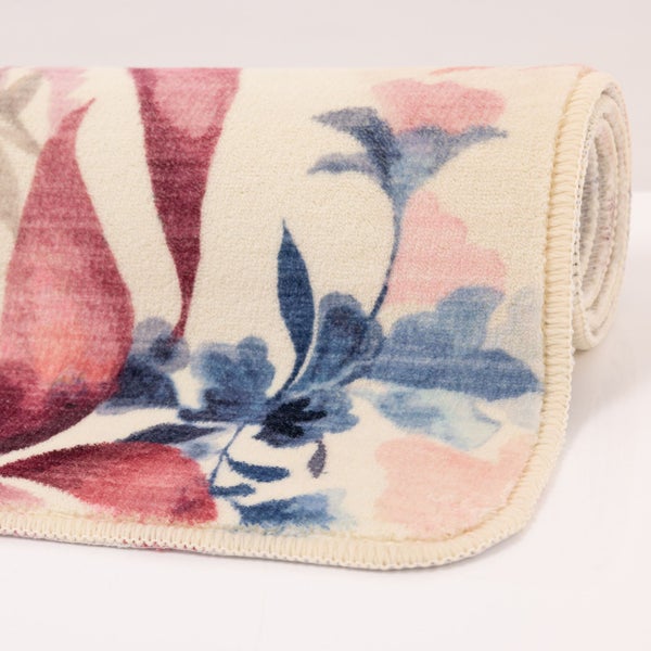 Aufgerollter Teppich mit floralem Muster in Rosa, Lila und Blau.