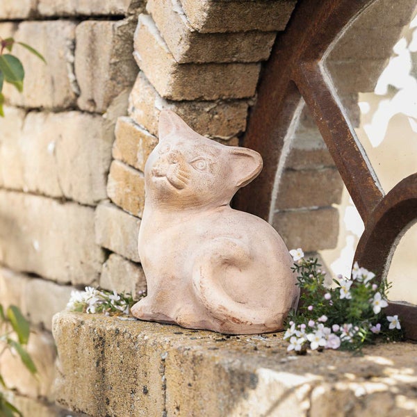 Dekorative Katzenfigur aus Stein auf einer Mauer