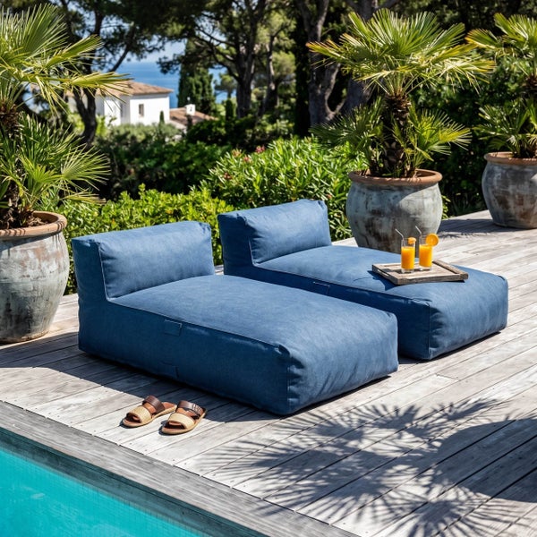 Zwei blaue Outdoor-Sitzsack-Liegen auf einer Holzterrasse am Pool mit Palmen in großen Töpfen.
