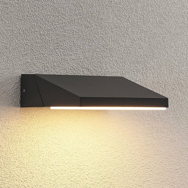 Moderne, keilförmige LED-Außenwandleuchte in Schwarz, an einer strukturierten Wand montiert mit nach unten gerichtetem Lichtstrahl.