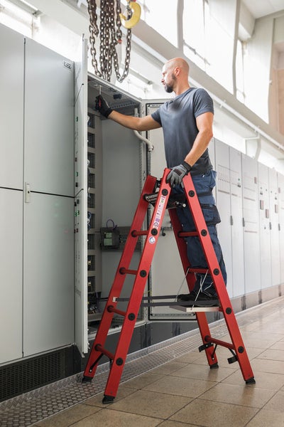 Mann auf einer Leiter bei der Arbeit an einer Schalttafel
