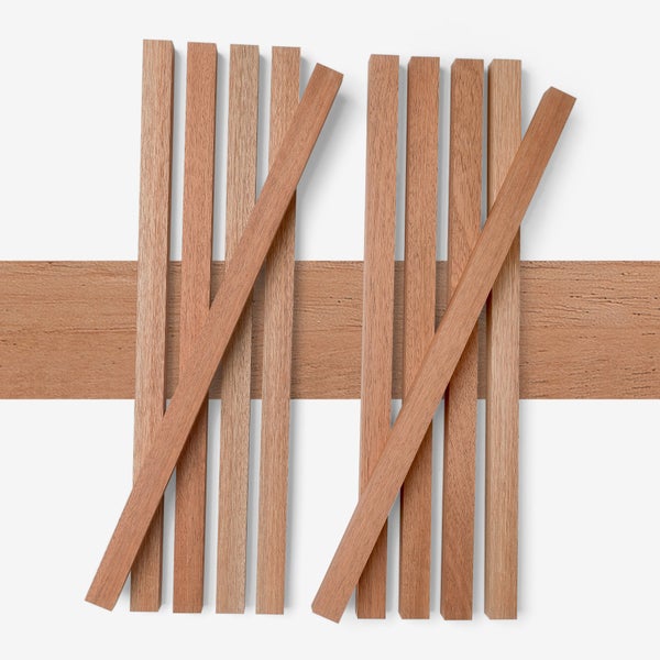 Rechteckige Holzleisten aus rötlichem Holz in verschiedenen Anordnungen auf einer Holzdiele.