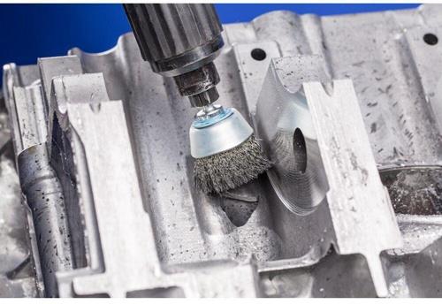 Drahtbürstenaufsatz an einer Bohrmaschine beim Reinigen eines Metallwerkstücks