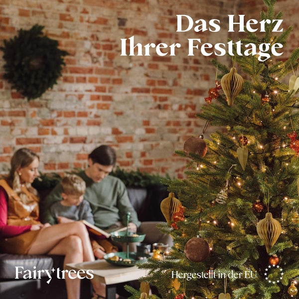 Eine Familie sitzt vor einem geschmückten Weihnachtsbaum von FairyTrees in einem Wohnzimmer mit Backsteinwand.