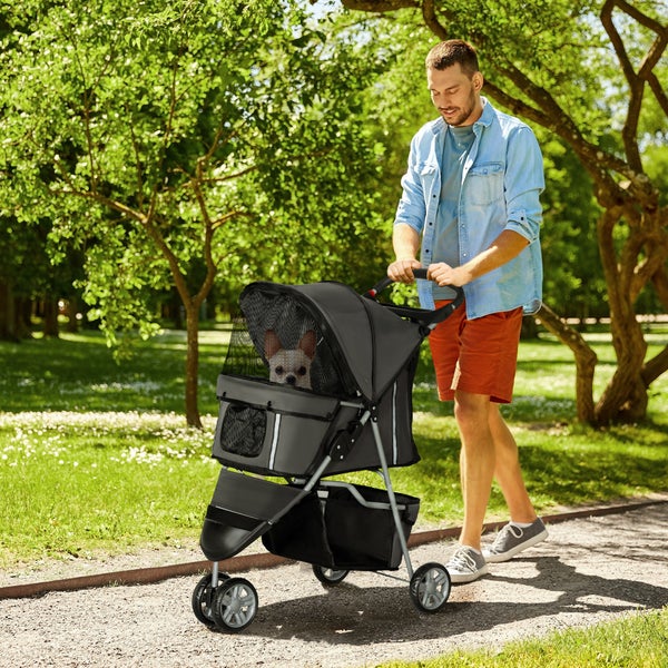 Mann schiebt einen grauen Tierkinderwagen mit einem Hund im Park.