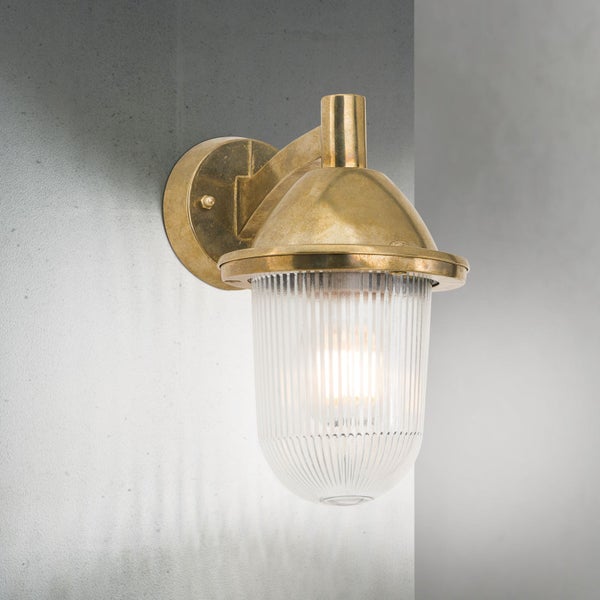 Außenwandleuchte aus Messing mit geriffeltem Glas und eingeschaltetem Leuchtmittel.