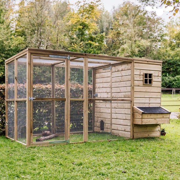 Freistehender Hühnerstall aus Holz mit Drahtgitter und Legenest im Garten.