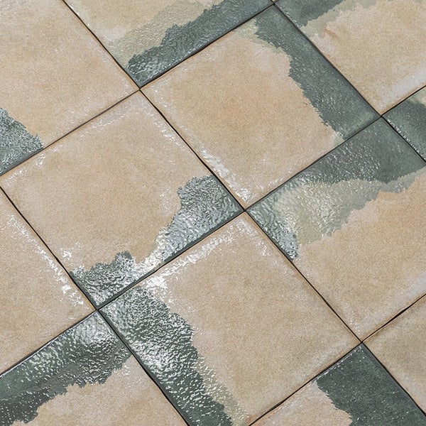 Quadratische Bodenfliesen mit einer strukturierten Oberflaeche und einem diagonalen Muster aus glatten und strukturierten Bereichen.