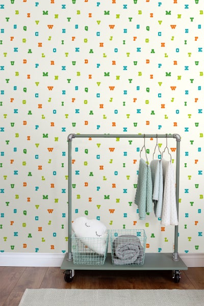 Kinderzimmer mit Mustertapete mit bunten Buchstaben und Kleiderständer mit Textilien
