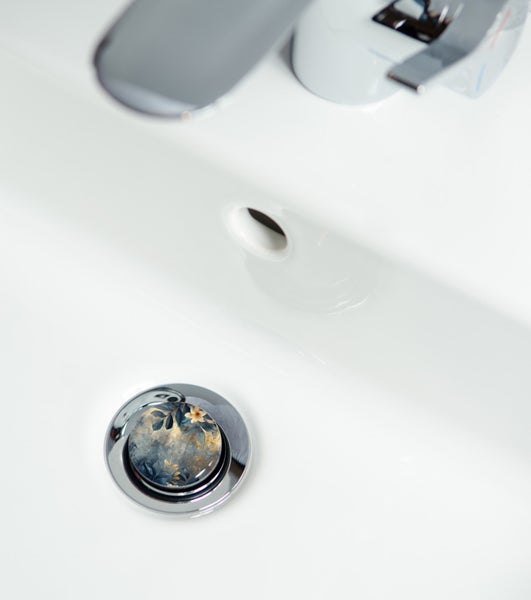 Waschbecken mit Wasserhahn und floral verziertem Ablaufstopfen