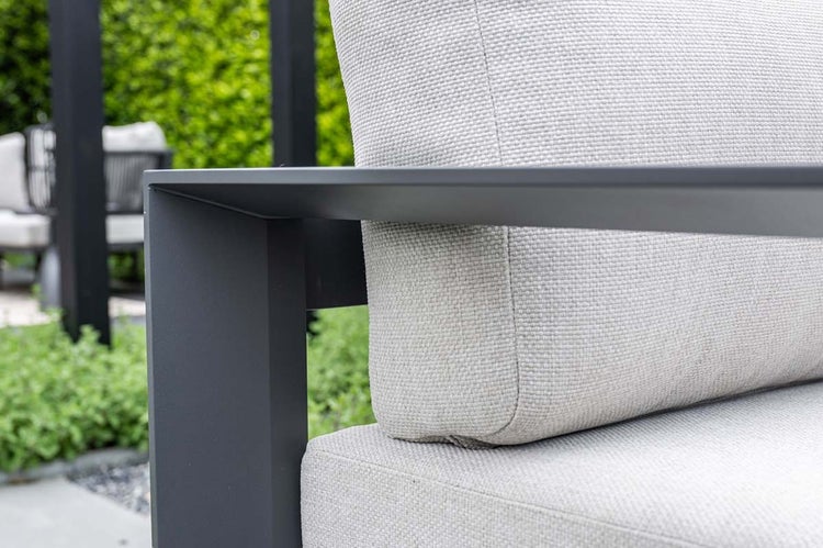 Nahaufnahme einer Gartenlounge mit einem eckigen Aluminiumgestell und einem strukturierten Stoffpolster.