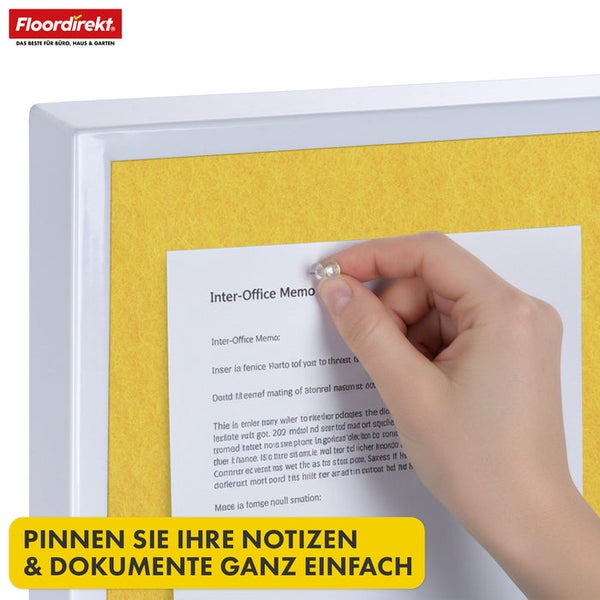 Gelbes Notizboard mit weißem Rahmen, eine Hand befestigt eine Notiz mit einer Reißzwecke.