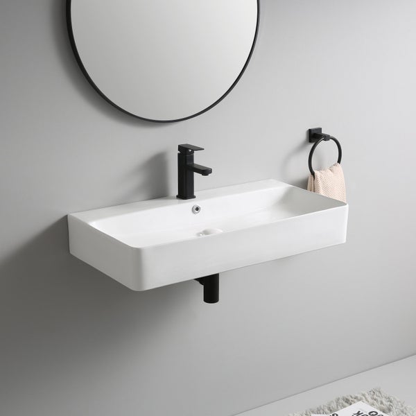 Modernes Badezimmer mit rechteckigem Wandwaschbecken aus Keramik, schwarzer Armatur, Rundspiegel und Handtuchring an grauer Wand.