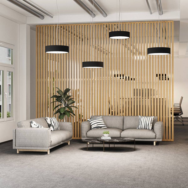 Moderner Loungebereich mit vier schwarzen Pendelleuchten, grauen Stoffsofas, Marmor-Couchtisch und einer Trennwand aus Holzlamellen.