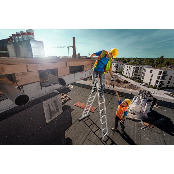Zwei Handwerker bei der Montage von Dachbaustoffen auf einer Baustelle mit einer Leiter.