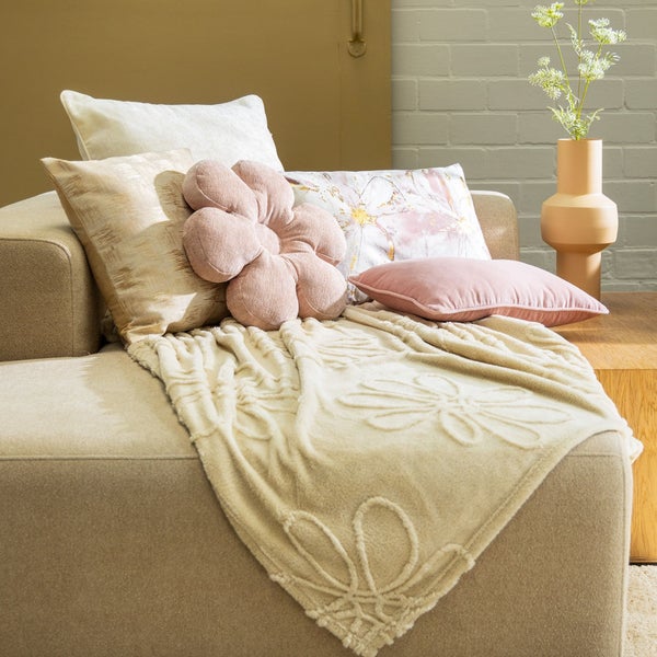 Dekoratives Wohnzimmer mit Sofa, Kissen und Blumenvase für eine gemütliche Atmosphäre.