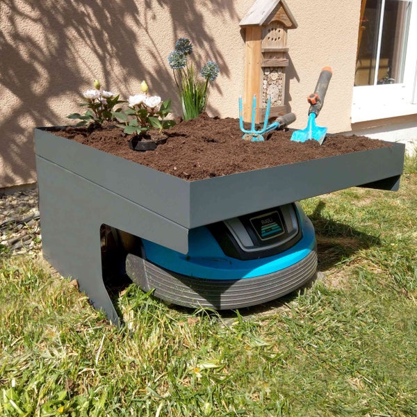 Szene mit einem Mähroboter unter einem Pflanzkasten mit Blumen und Gartengeräten