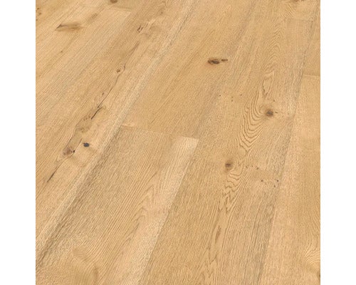 Heller Wohnraum mit Holzboden, Sofa, Sesseln und offener Küche.