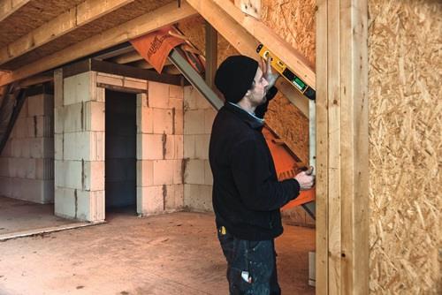 Handwerker mit Wasserwaage beim Bau eines Holzhauses