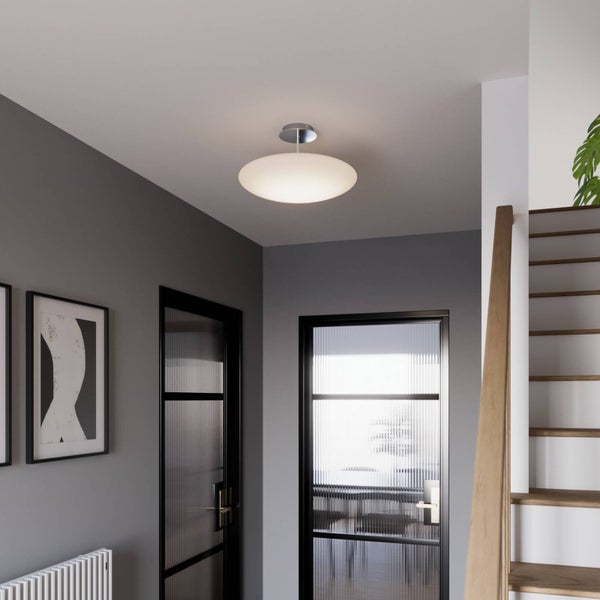 Oval-förmige Deckenleuchte in einem hellen, modernen Flur mit Glastüren und einer Holztreppe.