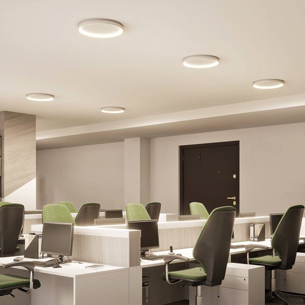 Modernes Büro mit mehreren Arbeitsplätzen und runden, flachen LED-Deckenleuchten, die für eine helle, gleichmäßige Beleuchtung sorgen.
