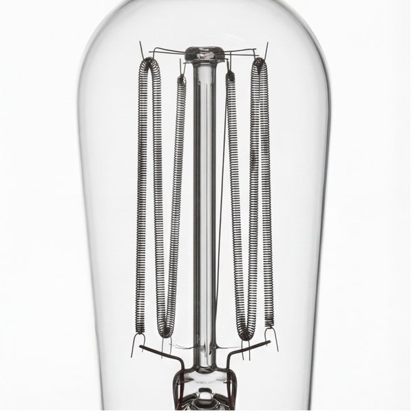 Nahaufnahme einer Vintage Glühbirne mit sichtbaren spiralförmigen Glühfäden in einer länglichen Glasform.