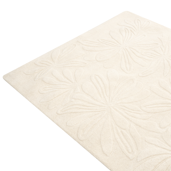 Beigefarbener Badeteppich mit floralem Reliefmuster aus Textil.