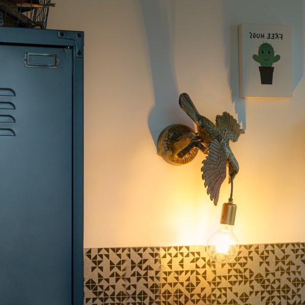 Wandleuchte mit Vogeldesign und dekorativer Glühbirne neben einem Metallschrank