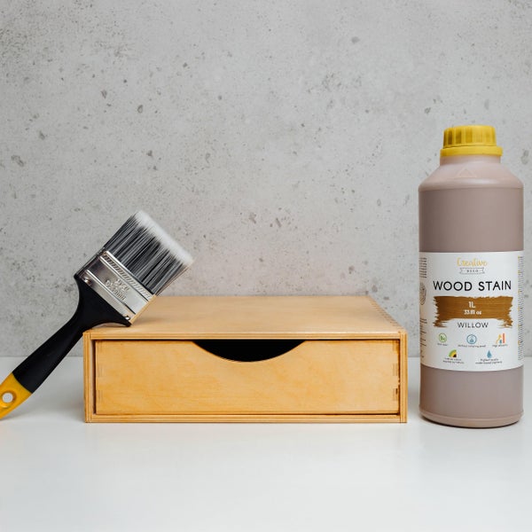 Creative Deco Holzbeize Willow 1 Liter Flasche neben einem Pinsel und einer kleinen Holzschubladenbox.