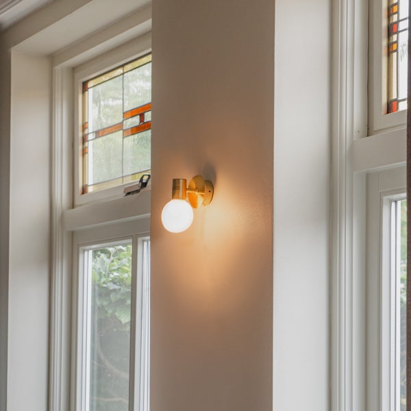 Wandleuchte mit runder Glühbirne neben einem Fenster
