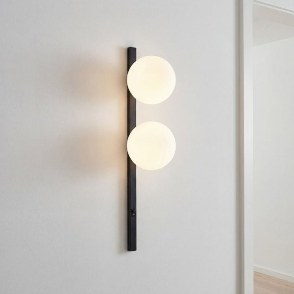 Moderne Wandleuchte mit schwarzer vertikaler Metallbasis und zwei weißen kugelförmigen Glasschirmen, inklusive Schalter.