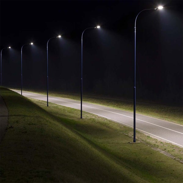 Reihe von Straßenlaternen beleuchtet einen Weg in der Nacht