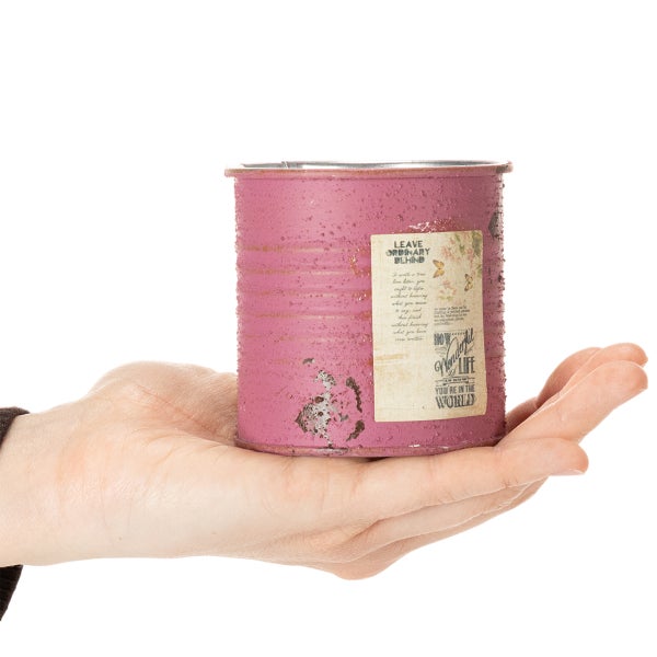 Dekorative Metalldose in Rosa mit Vintage-Design und Etikett in einer Hand.