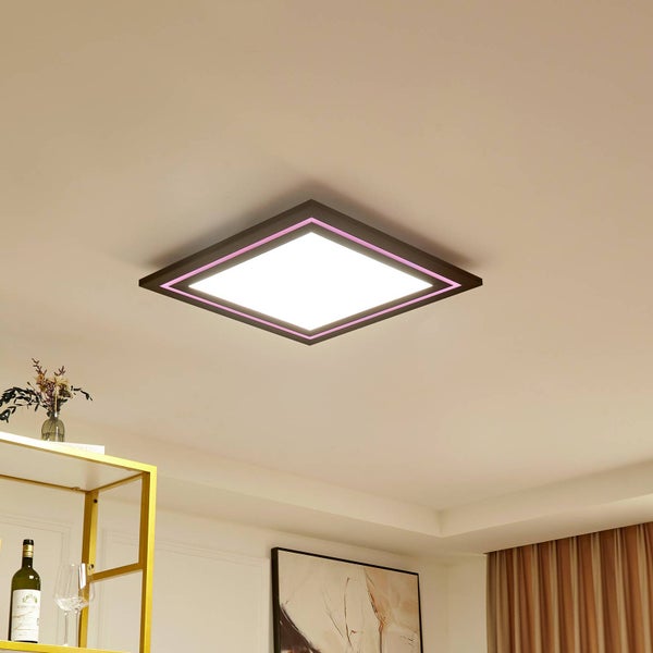 Moderne quadratische LED-Deckenleuchte mit weißem Lichtpaneel und rosa Leuchtrahmen, montiert an einer Zimmerdecke in einem hellen Raum.