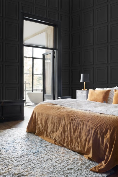 Schlafzimmer mit Bett, Nachttisch und strukturierten, dunklen Wandpaneelen