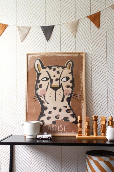 Dekoratives Kinderzimmer mit Leopard-Wandkunst, Wimpelkette und Spielzeug auf einem schwarzen Tisch.