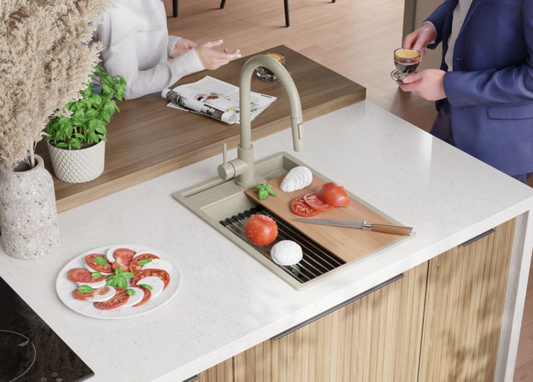 Küchenszene mit Spüle, Armatur, Schneidebrett mit Tomaten und Mozzarella sowie einem Teller Caprese.