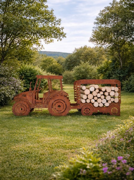 Gartendeko-Traktor aus Edelrost mit Anhänger als Kaminholzregal auf einer Rasenfläche.