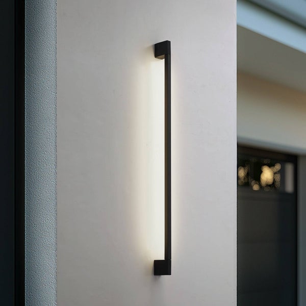 Moderne, schwarze LED-Außenwandleuchte in schmalem, vertikalem Design mit warmweißem Licht an einer Hauswand.