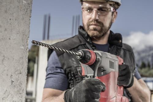 Handwerker bohrt mit einem Bohrhammer in eine Betonwand