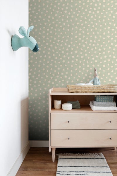 Babyzimmer mit Wickelkommode, Sternchentapete und Stofftierkopf an der Wand.