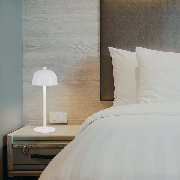 Szene eines Nachttisches mit einer modernen weißen Tischlampe neben einem Bett