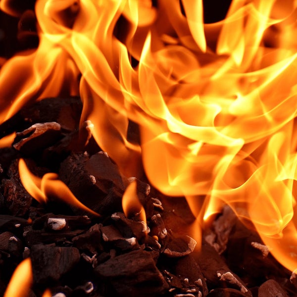 Brennende Holzkohle in einem Grill mit lodernden Flammen.