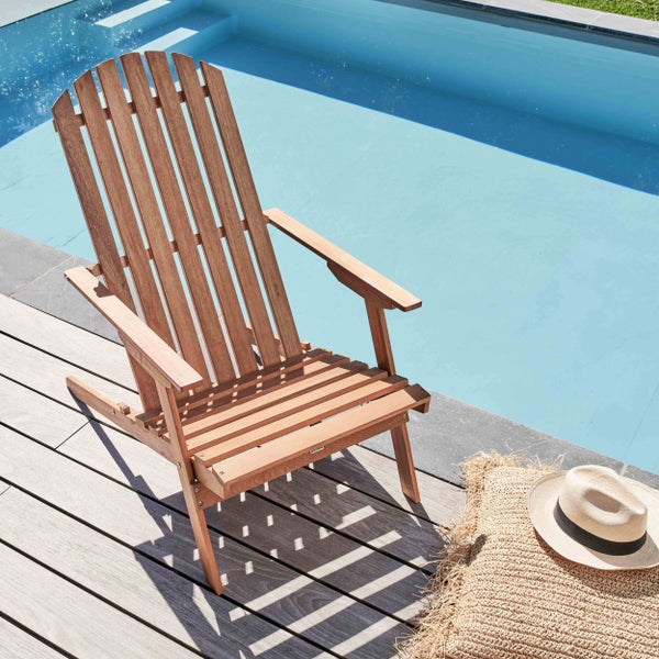 Adirondack-Gartensessel aus Holz auf einer Holzterrasse am Pool mit Sonnenhut und Kissen.